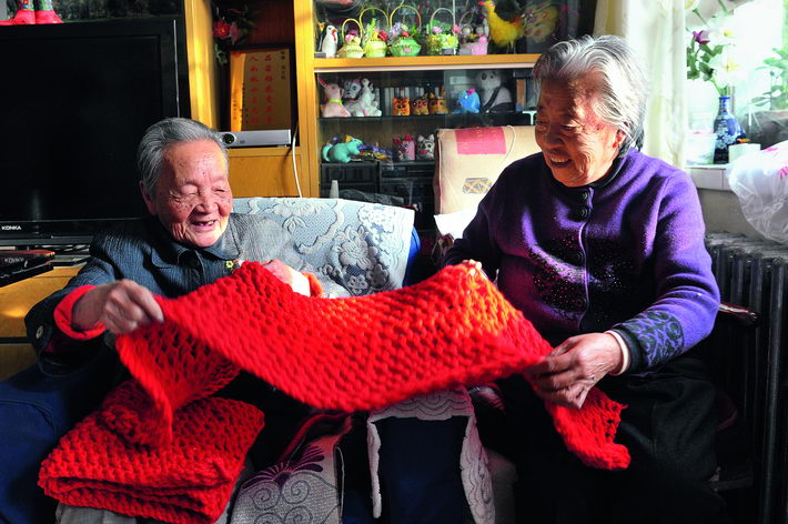 November 19, 2013: 100-year-old Su Fengzhu (left) and her 83-year-old friend Zhang Yunying inspect a scarf they have just finished knitting, in Yinchuan City. VCG